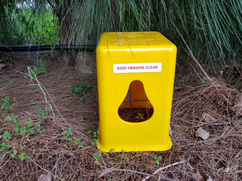 Timms trap for possum control, sitting on the ground.