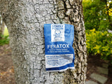 A filled Feratox Bio Bag for possum control stapled onto a tree.
