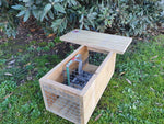 DOC150 trap for rat, stoat, and hedgehog control, sitting in wooden housing.