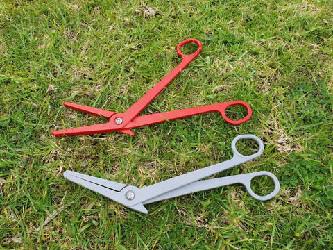 Terra Don trapping tools - a red and a grey tool, lying on the grass.
